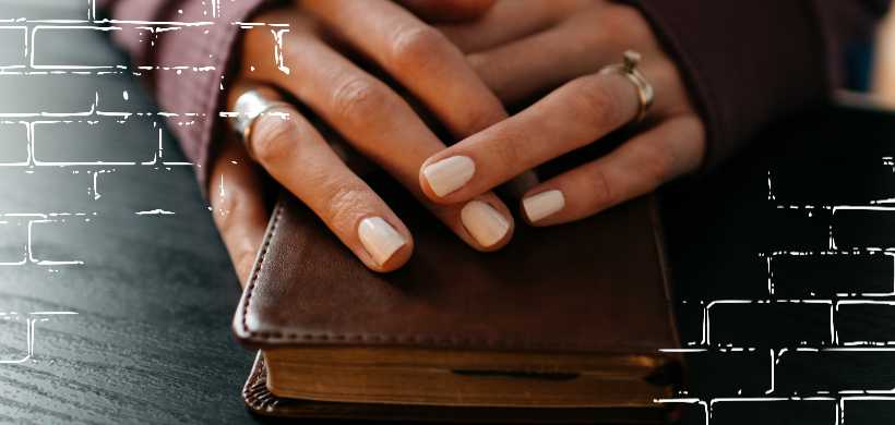 las manos de una mujer encima de una biblia pequeña